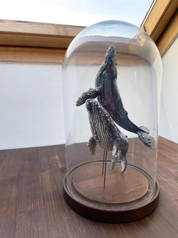 Humpback whales couple on a wooden stand under glass cloche, made of ceramics