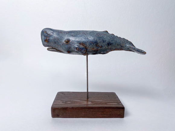 Sperm whale made of ceramics, on a wooden stand